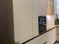Bele fronte vgradnega hladilnika - Kuhinja v L kompoziciji z izvlečnimi predali in šankom