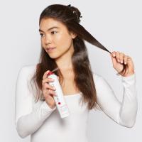Sprej Paul Mitchell Hot Off The Press v ženski roki med nanosom