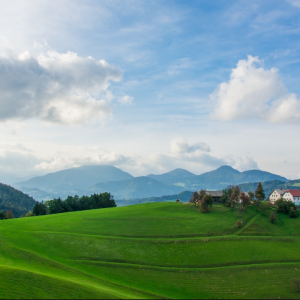 Pogled s Kovskega vrha s kmetijo v ospredju ter značilno krajino ter poljanskimi očaki v ozadju Foto: Uroš Gantar
